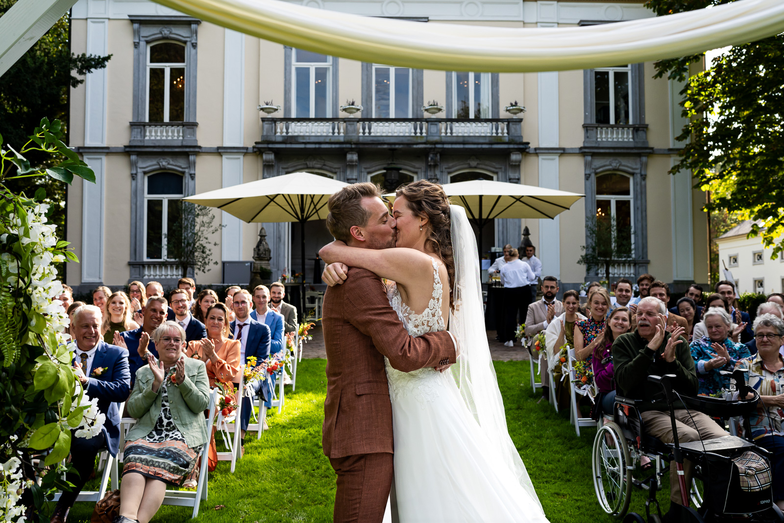 Bruid en bruidegom delen een kus tijdens hun romantische trouwceremonie bij Landgoed Wolfslaar in Breda.